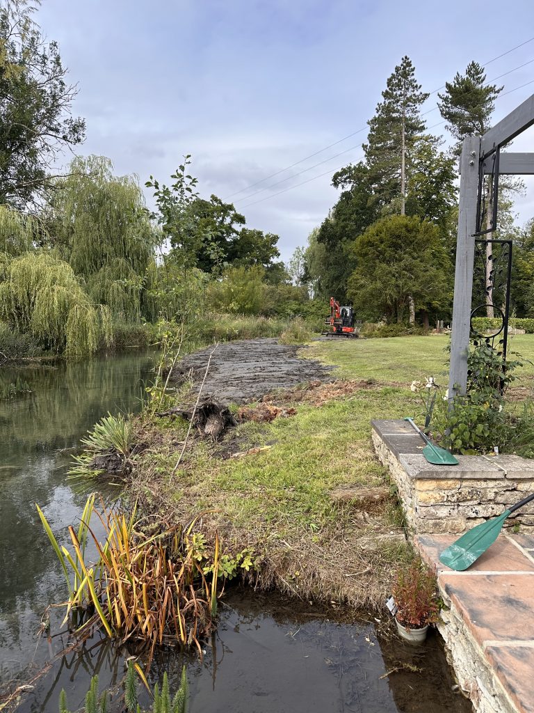 Riverside landscape with excavator working along the waterway bank
