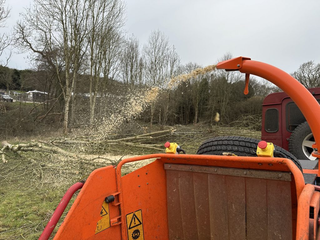 Wood chipper in action, processing branches on a rural worksite