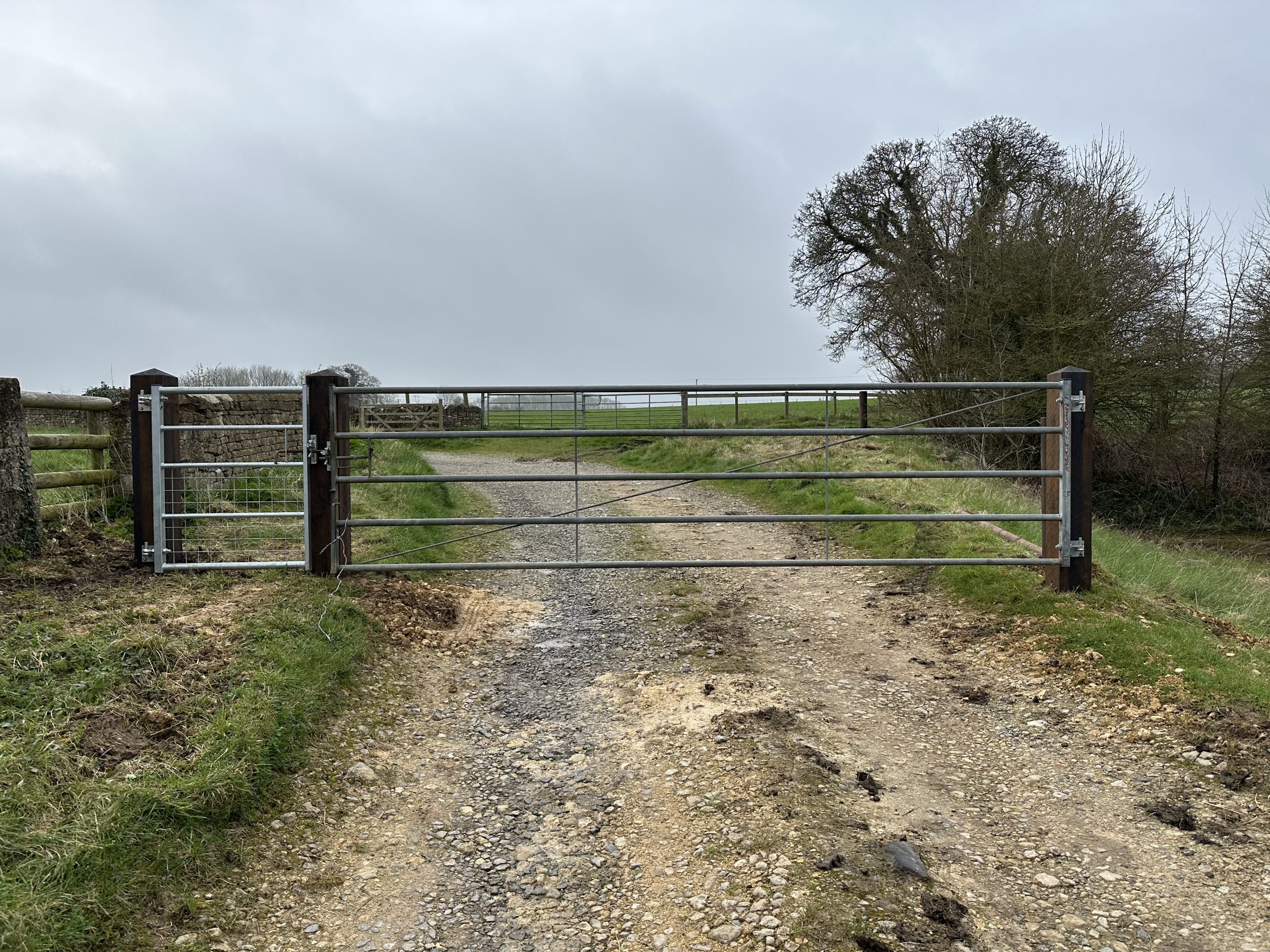Metal farm gate on a country lane with pasture beyond