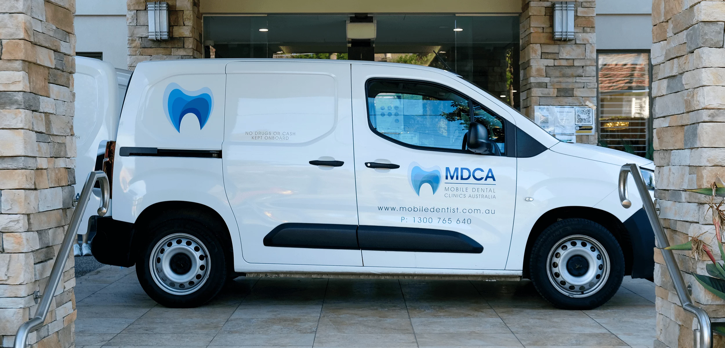 MDCA white service van parked at a facility entrance ready to deliver mobile dental services