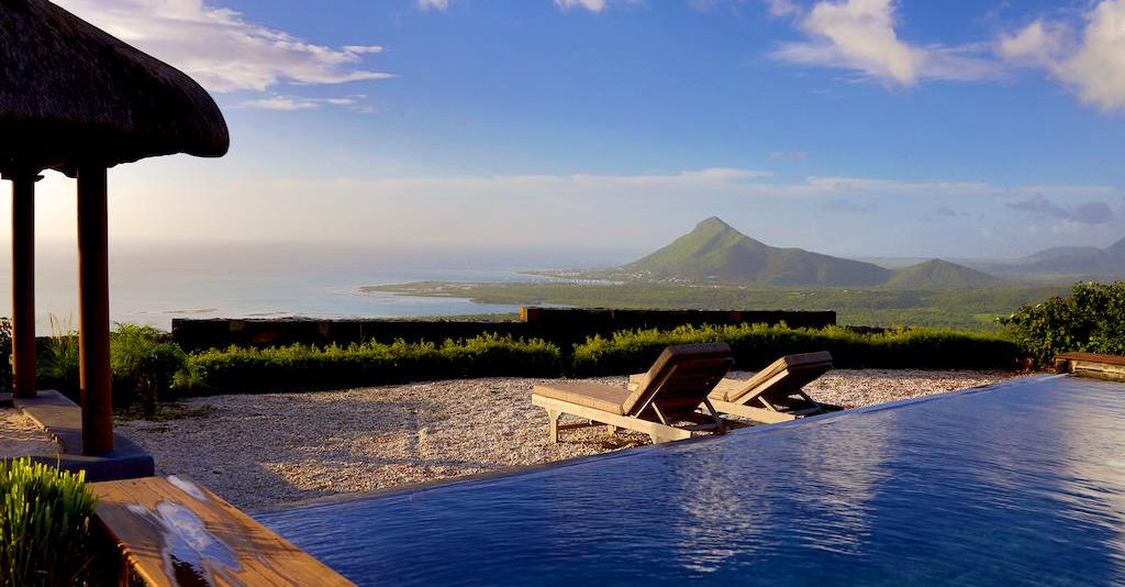 Infinity pool at Lakaz Chamarel with lounge chairs overlooking the coastal landscape and mountains