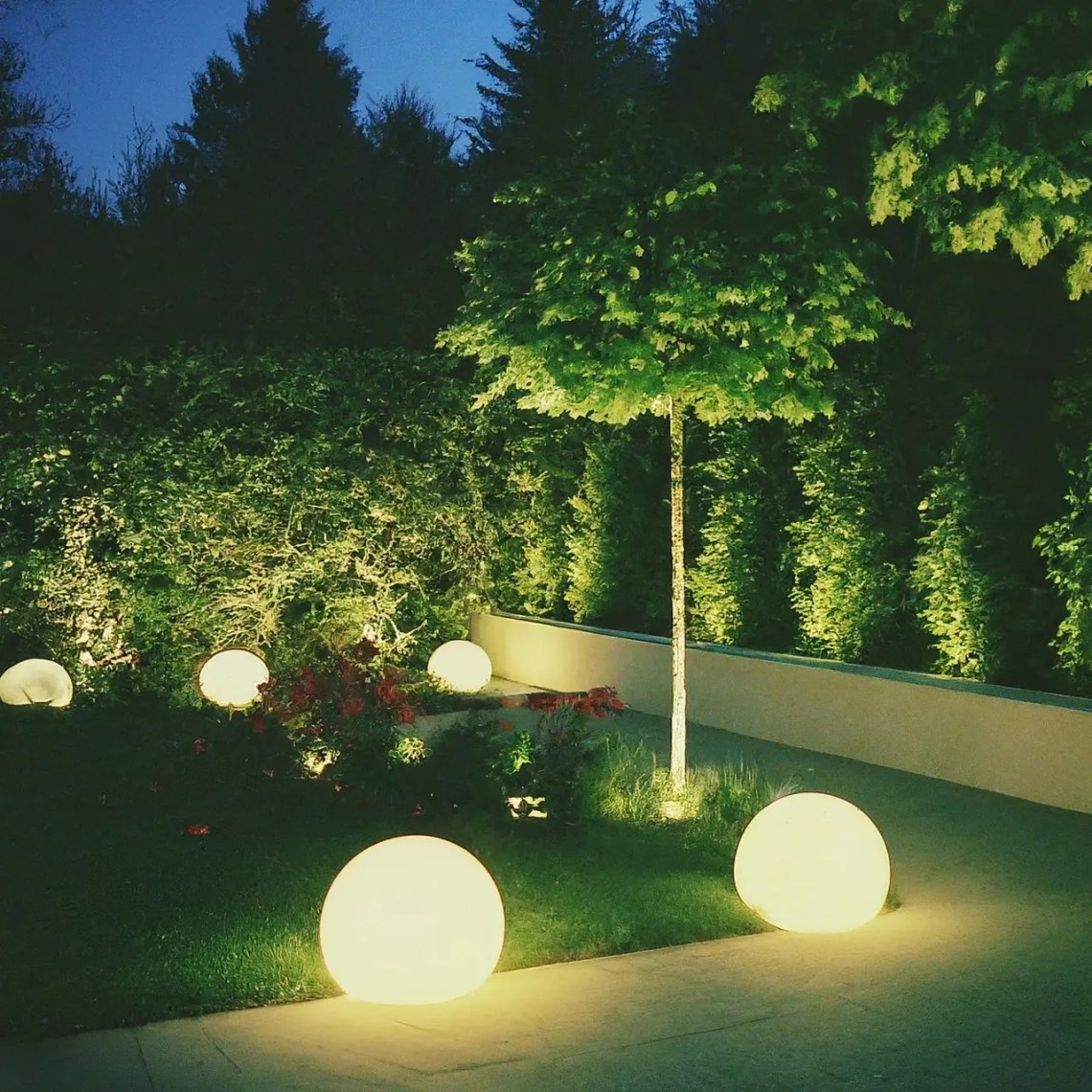 Manicured garden with spherical pathway lights and LED uplighting on shrubs and small trees