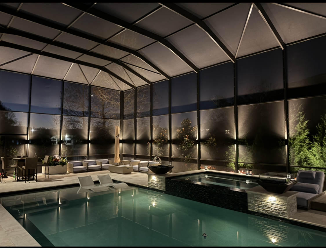 Luxury indoor pool with screened enclosure and professional LED lighting at night