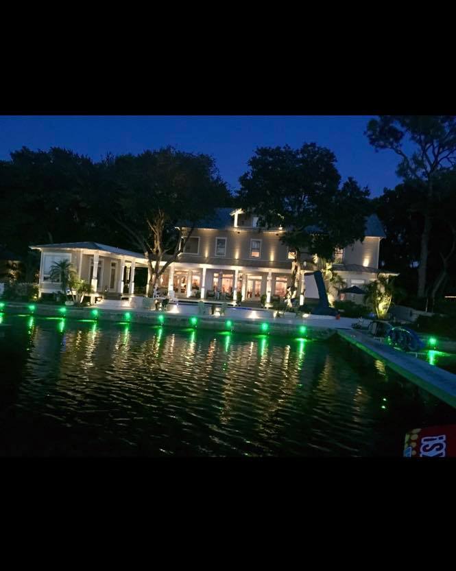 Waterfront resort building at night with green accent lighting reflecting on lake surface