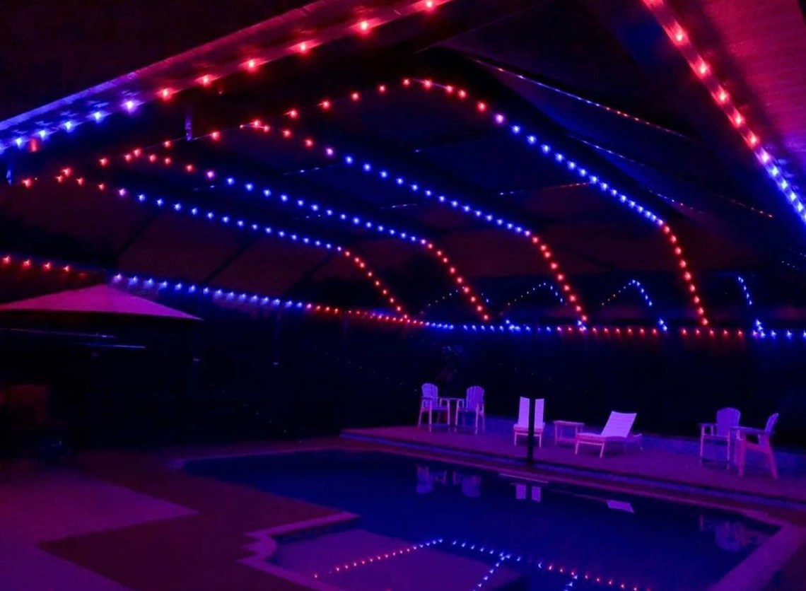 Screened pool cage at night with warm LED accent lighting around outdoor living area