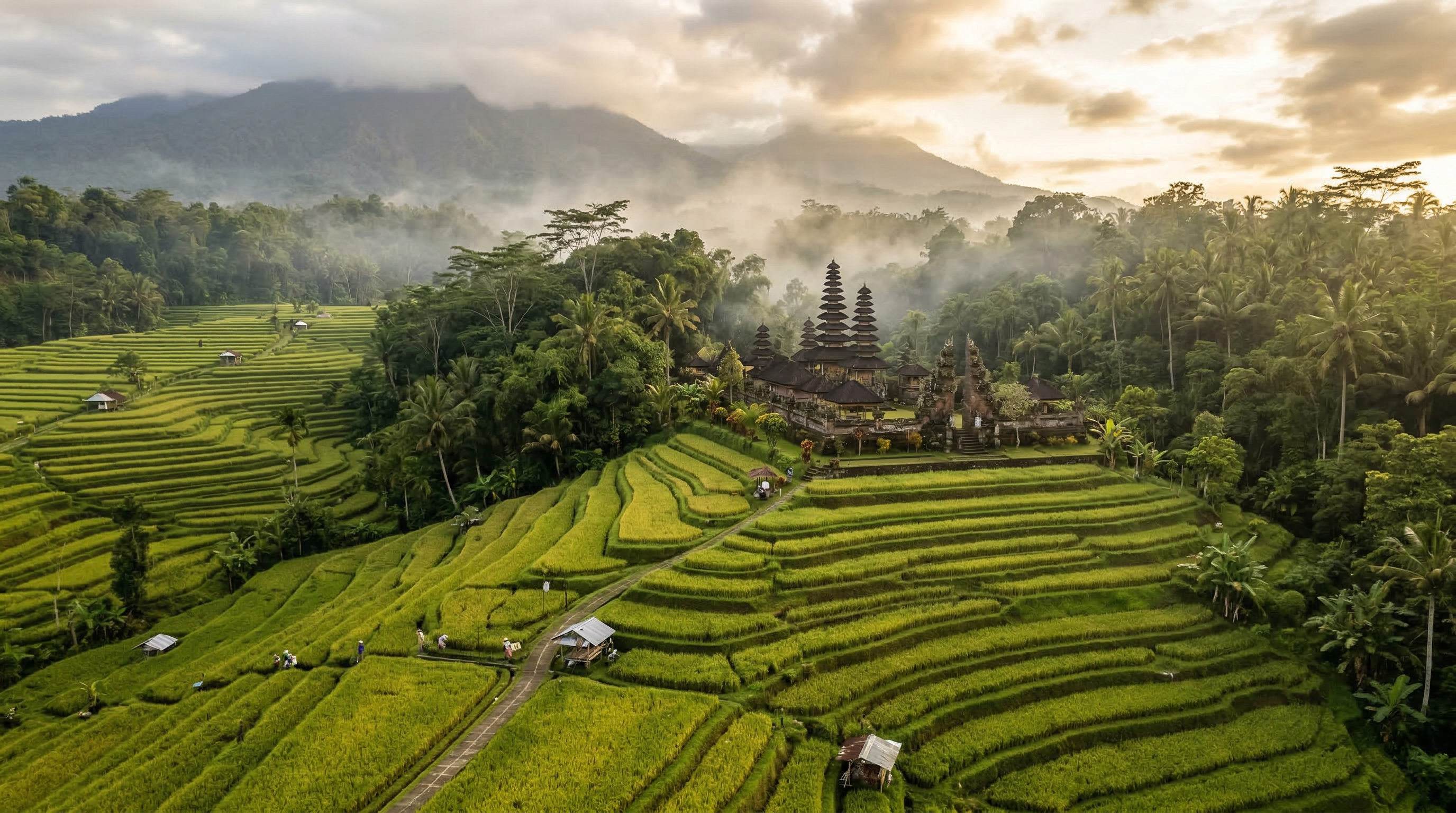Lush Bali rice terraces with ancient temple surrounded by tropical jungle at golden sunrise