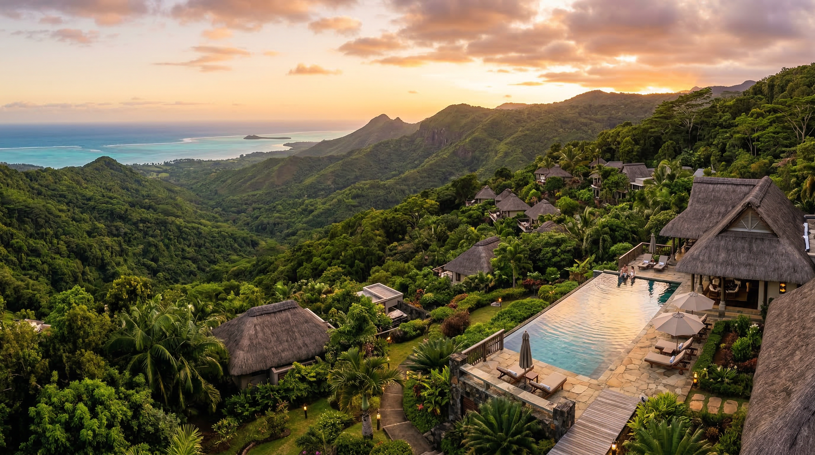 Aerial view of Lakaz Chamarel Exclusive Lodge surrounded by lush jungle with ocean and mountain views at sunset