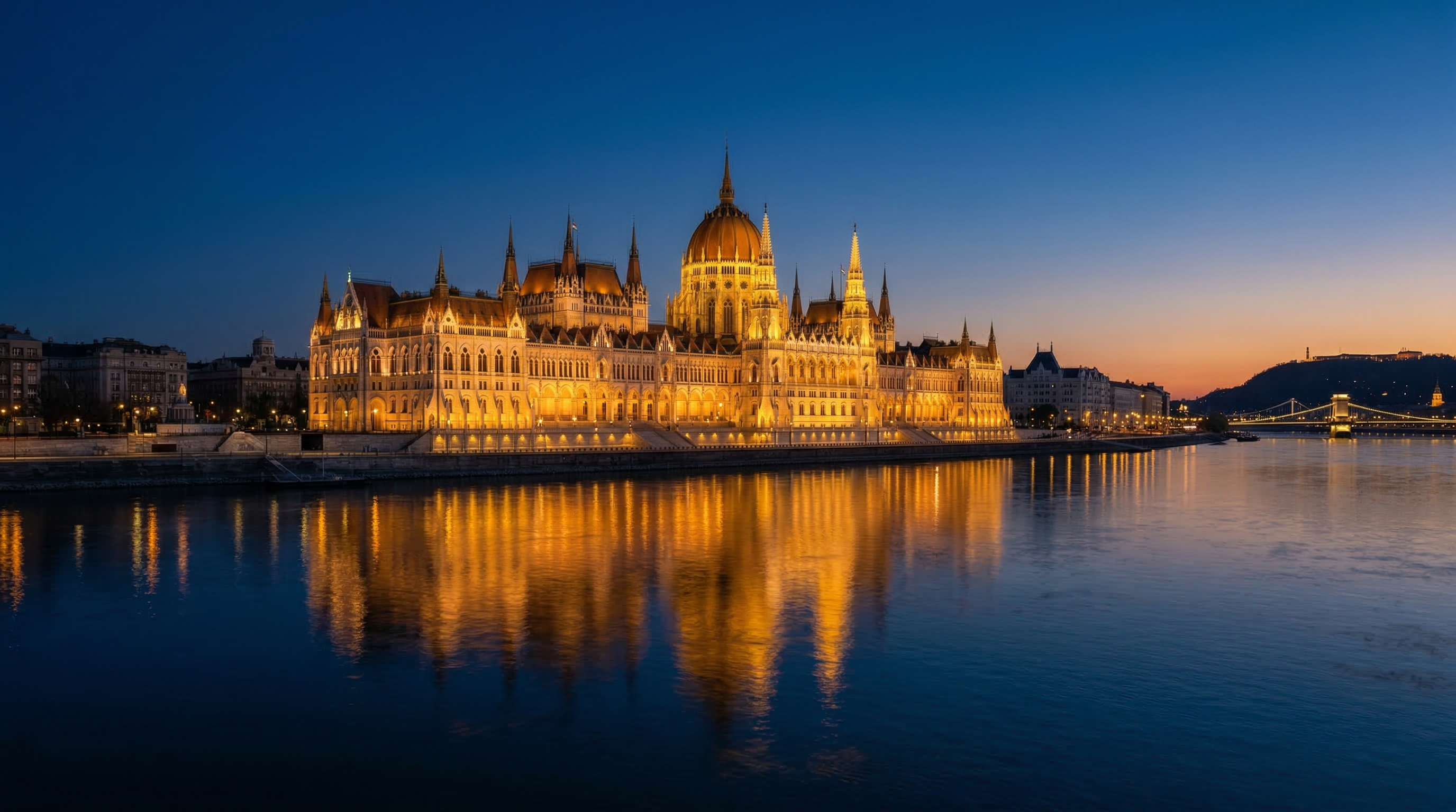 Hungarian Parliament building illuminated at dusk, reflected in the Danube River