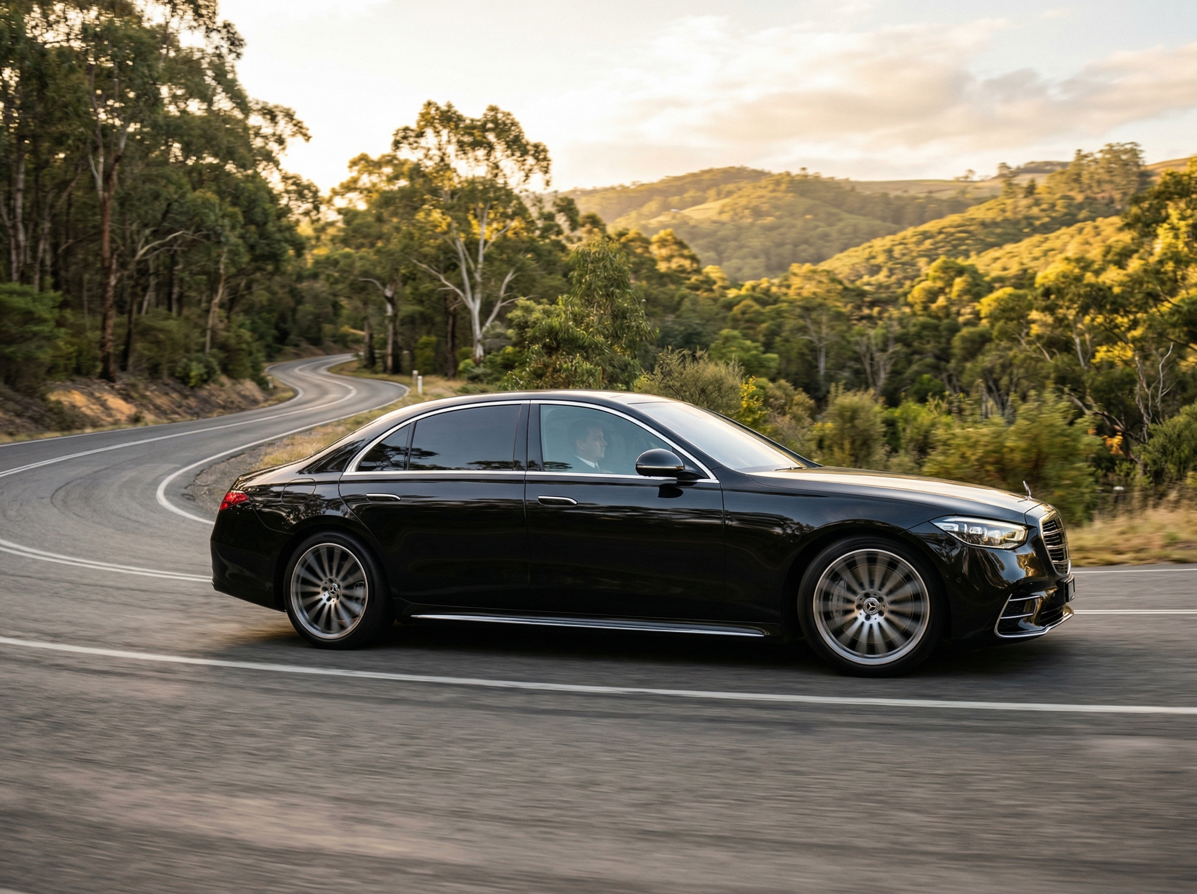Luxury chauffeured sedan driving through scenic Adelaide Hills winding road