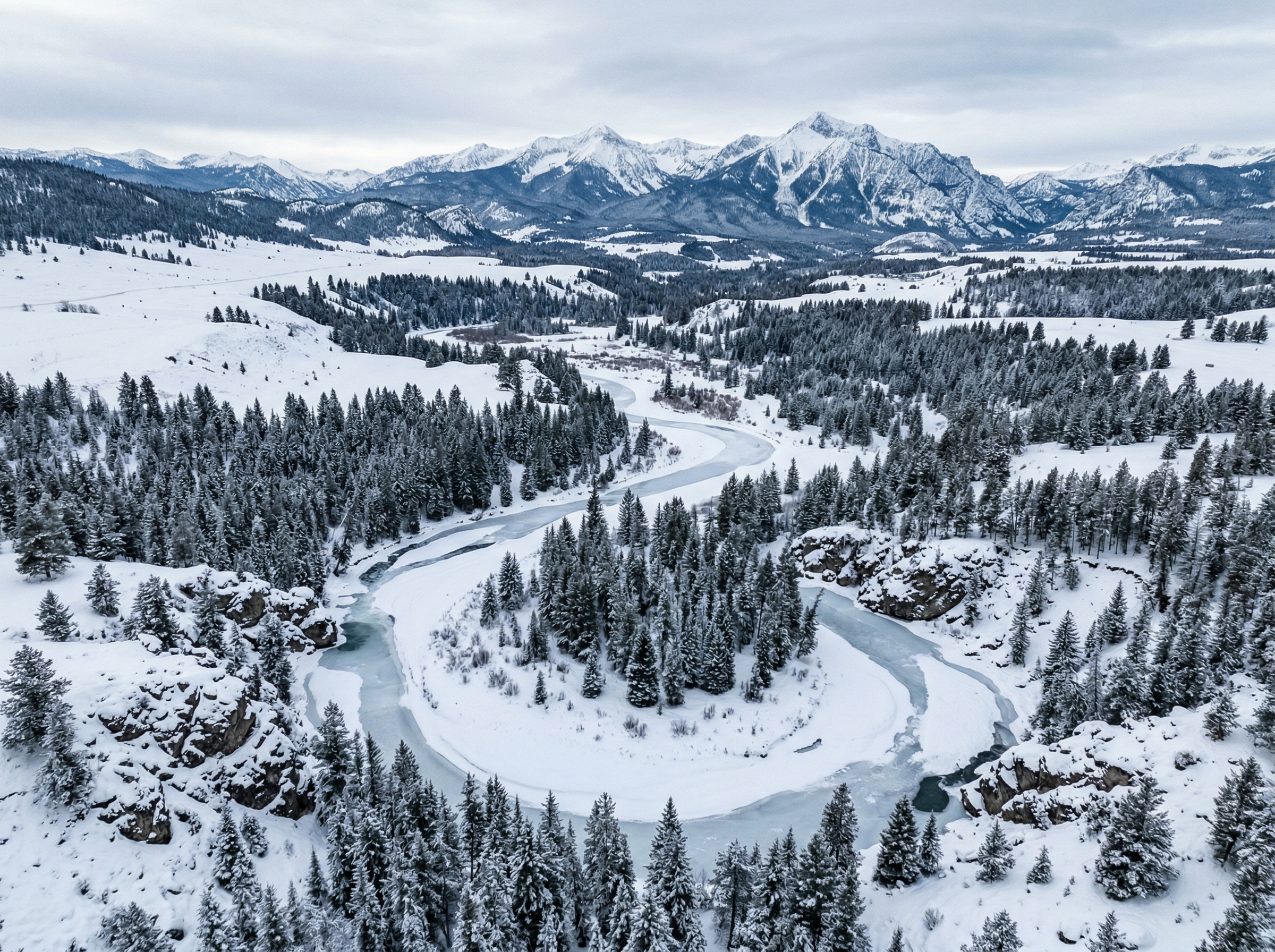 Frozen river winding through a snowy Montana valley with snow-capped peaks in the distance